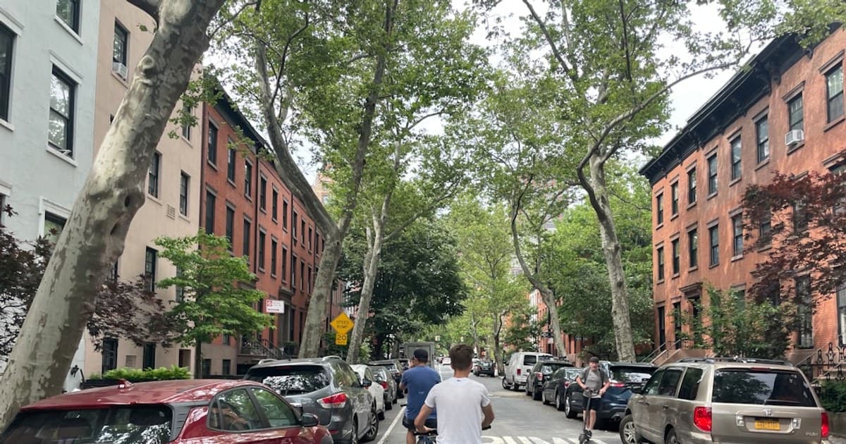 a group of people riding bicycles on a street between buildings