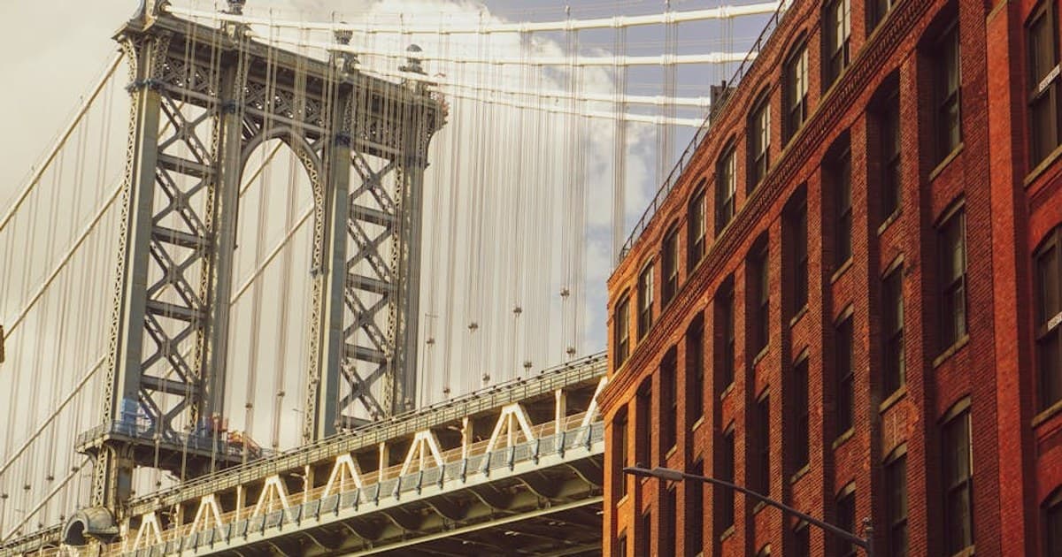 View of Manhattan Bridge adjacent to red brick building in DUMBO, Brooklyn.