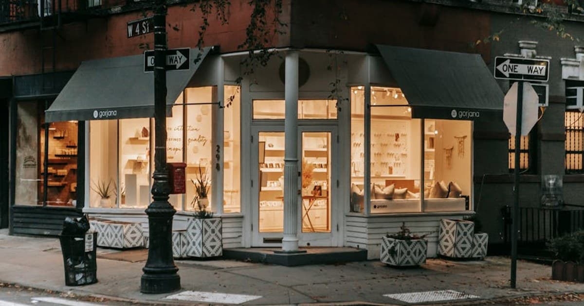 Facade of lit shop on street near crosswalk and roadway on street in modern city in soft daylight
