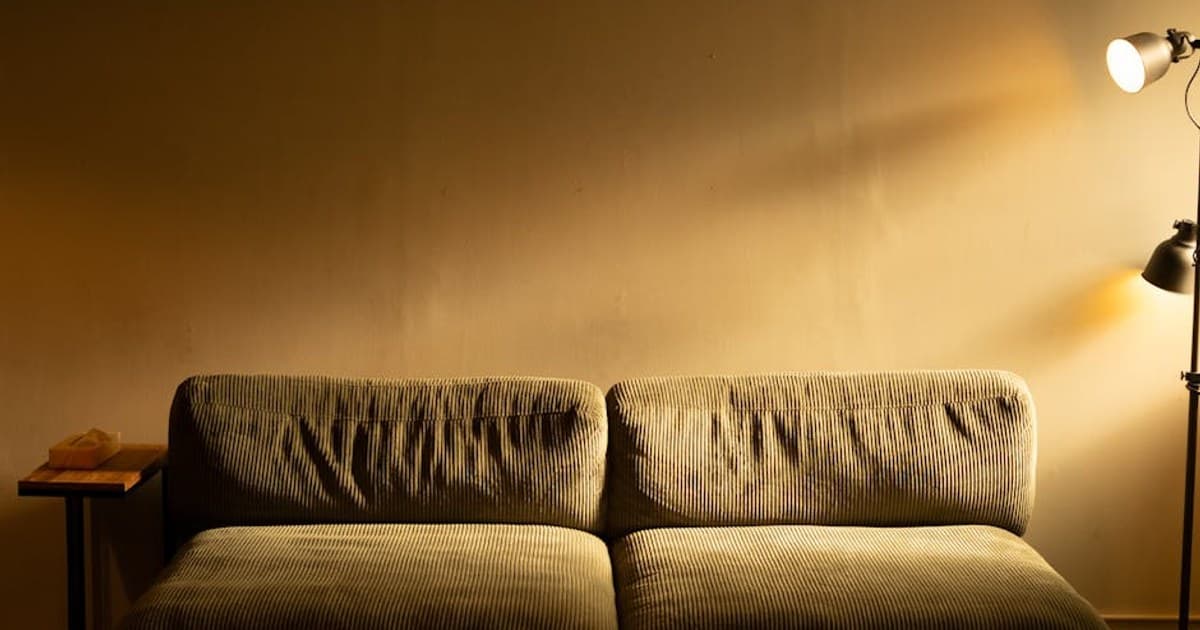 Warmly lit living room featuring a comfortable sofa and a floor lamp casting a soft glow.