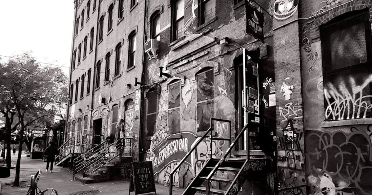 Dramatic black and white photo of a graffiti-covered alley in Brooklyn, showcasing urban art and architecture.