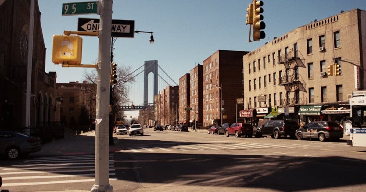 City street view with buildings, traffic lights, and a bridge under a clear sky.