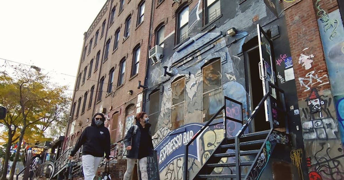 Urban street view in Brooklyn with graffiti and pedestrians walking by an Espresso Bar.
