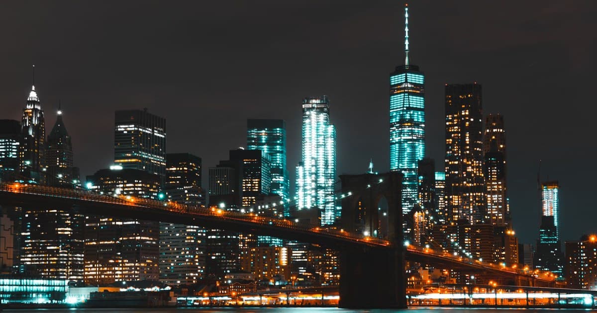 Captivating night skyline of New York City with Brooklyn Bridge and skyscraper reflections.