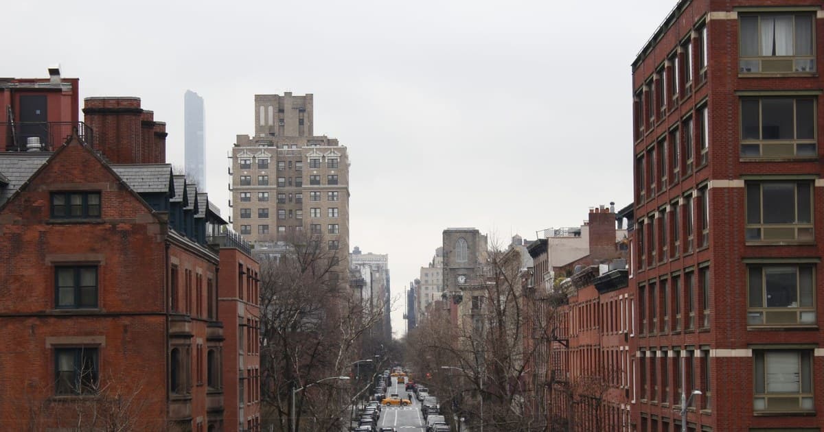 A bustling city street lined with historic brick buildings and parked cars.