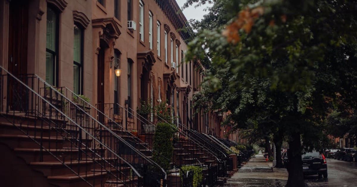 A rainy day in a historic New York neighborhood with classic brownstone buildings.