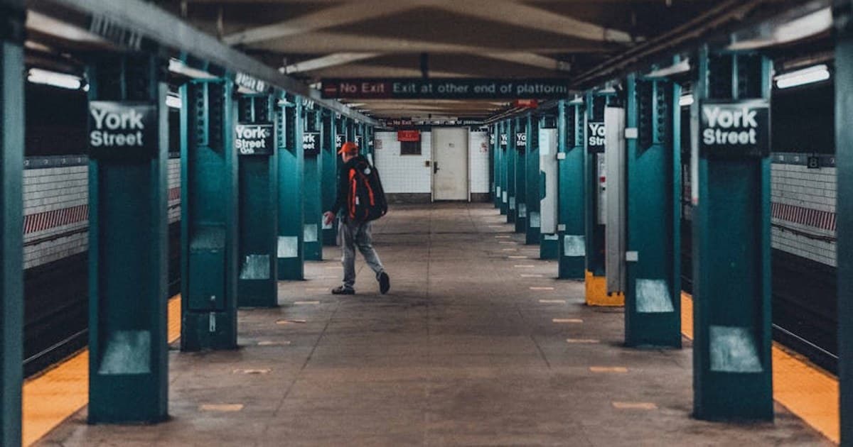A candid shot of a man walking through York Street Subway Station in New York City.