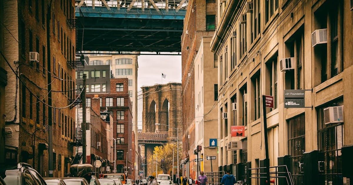 Urban view of a Brooklyn street under the bridge with city life and architecture.