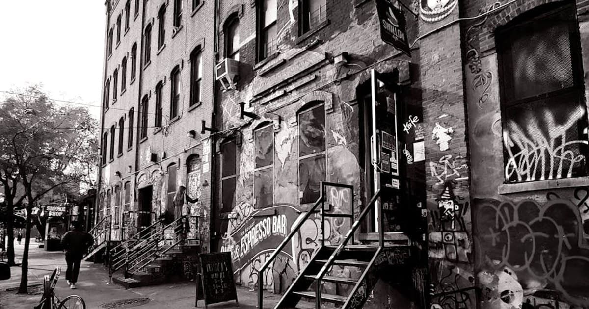 Black and white photo of a graffiti-covered alley in Brooklyn, showcasing urban street art.