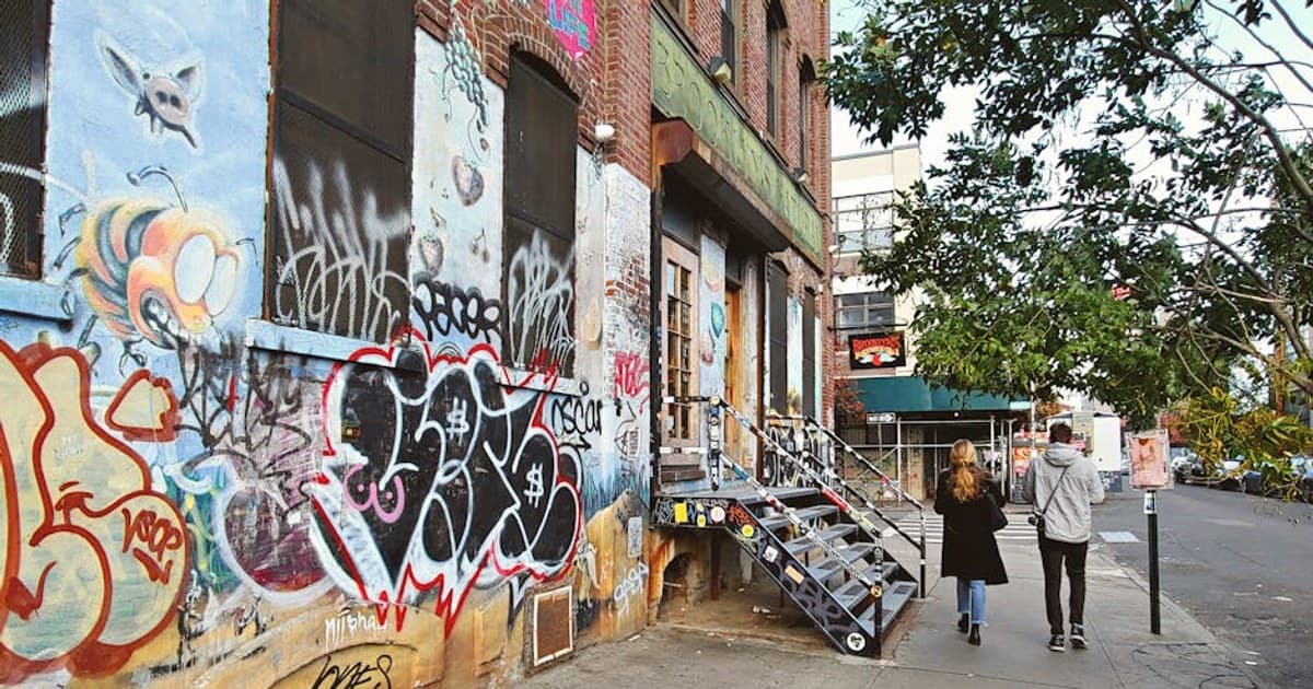 Colorful graffiti in a Brooklyn alley with two people walking, capturing urban street art.