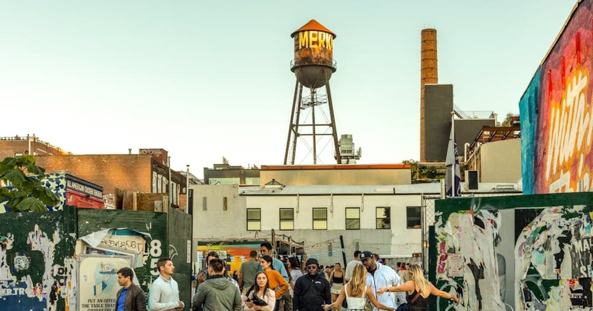 A lively outdoor gathering in Brooklyn, featuring diverse people and street art.