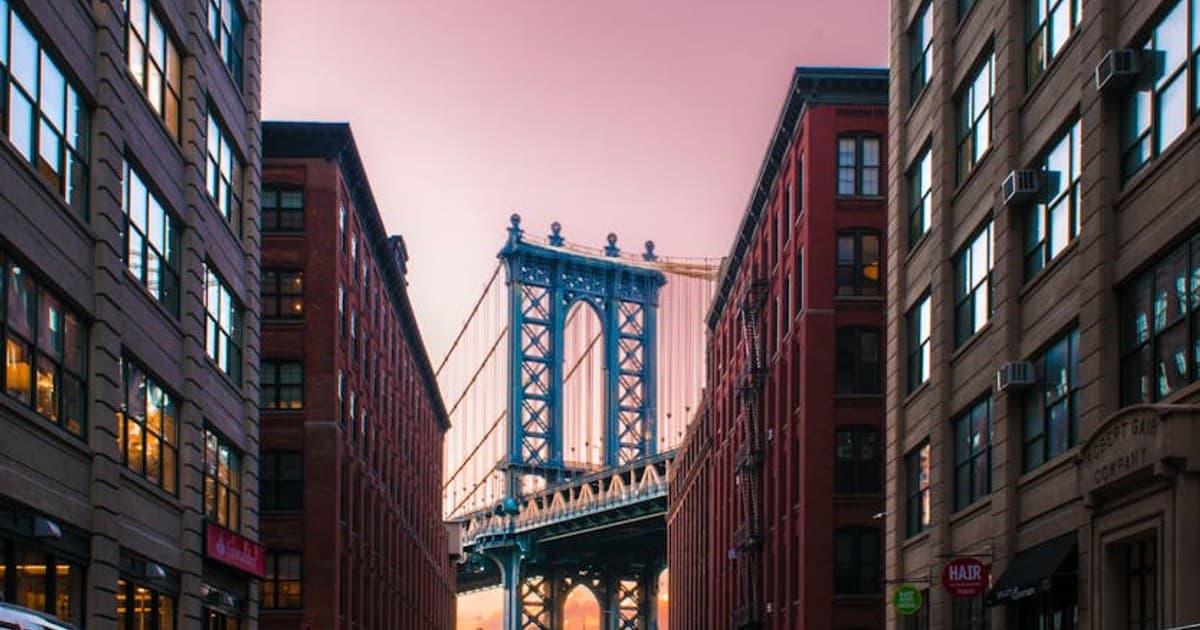 A stunning view of the Manhattan Bridge framed by city buildings at sunset in New York City.