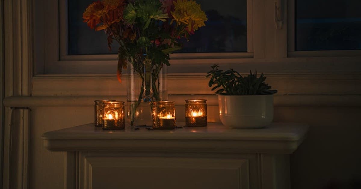 A warm, candlelit ambiance with vibrant flowers on a windowsill, creating a serene night scene.