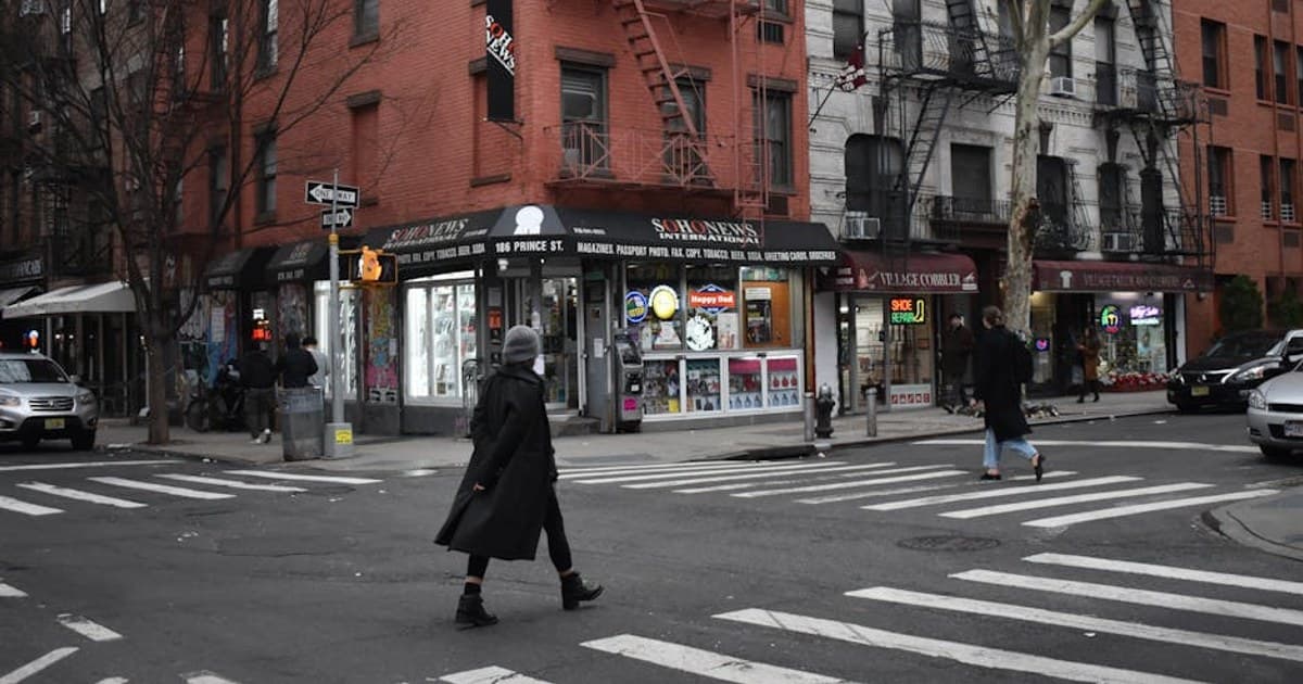 Pedestrians crossing a street at an intersection in Brooklyn, NYC with shops and apartments.