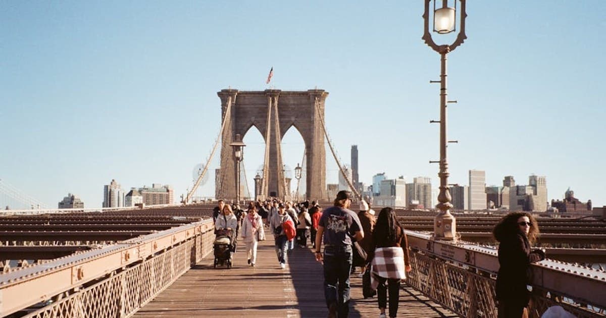 People strolling on the iconic Brooklyn Bridge in New York City with skyline views.