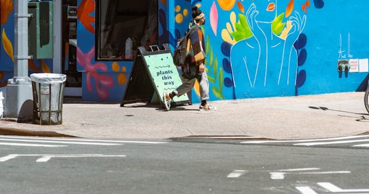 A vibrant mural on a city street corner featuring a woman walking past colorful graffiti.