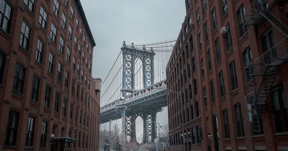 Captivating snowy view of Manhattan Bridge from Dumbo, NYC, framed by red brick buildings.