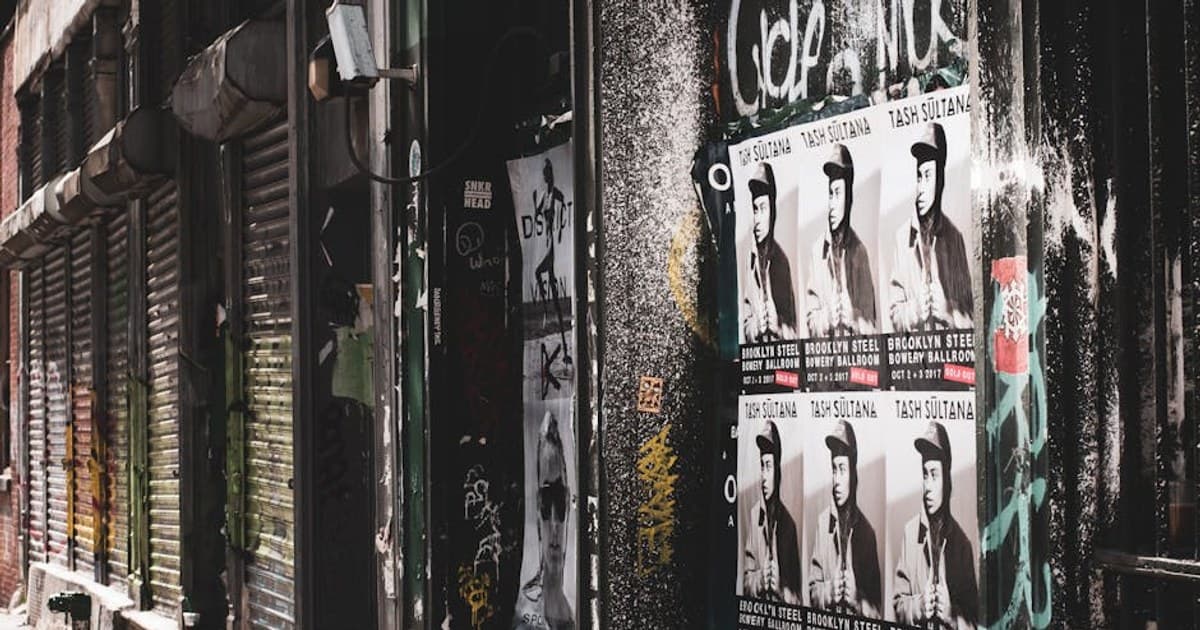 Gritty urban street shot in New York City featuring posters and graffiti in a deserted alleyway.