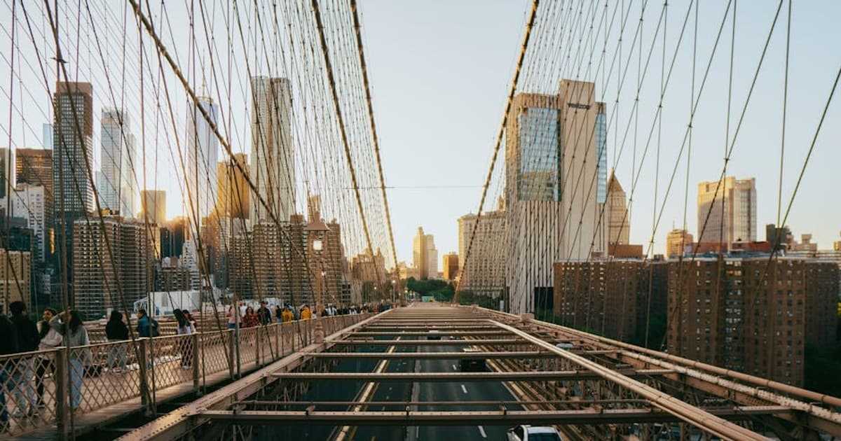 View of Brooklyn Bridge with Manhattan skyline at sunset, capturing urban life and architecture.