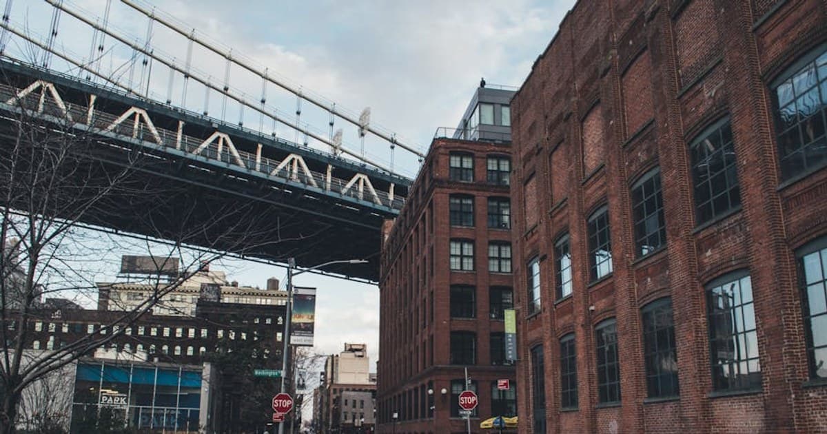 Brick buildings and Manhattan Bridge in Brooklyn, New York City on a lively street.