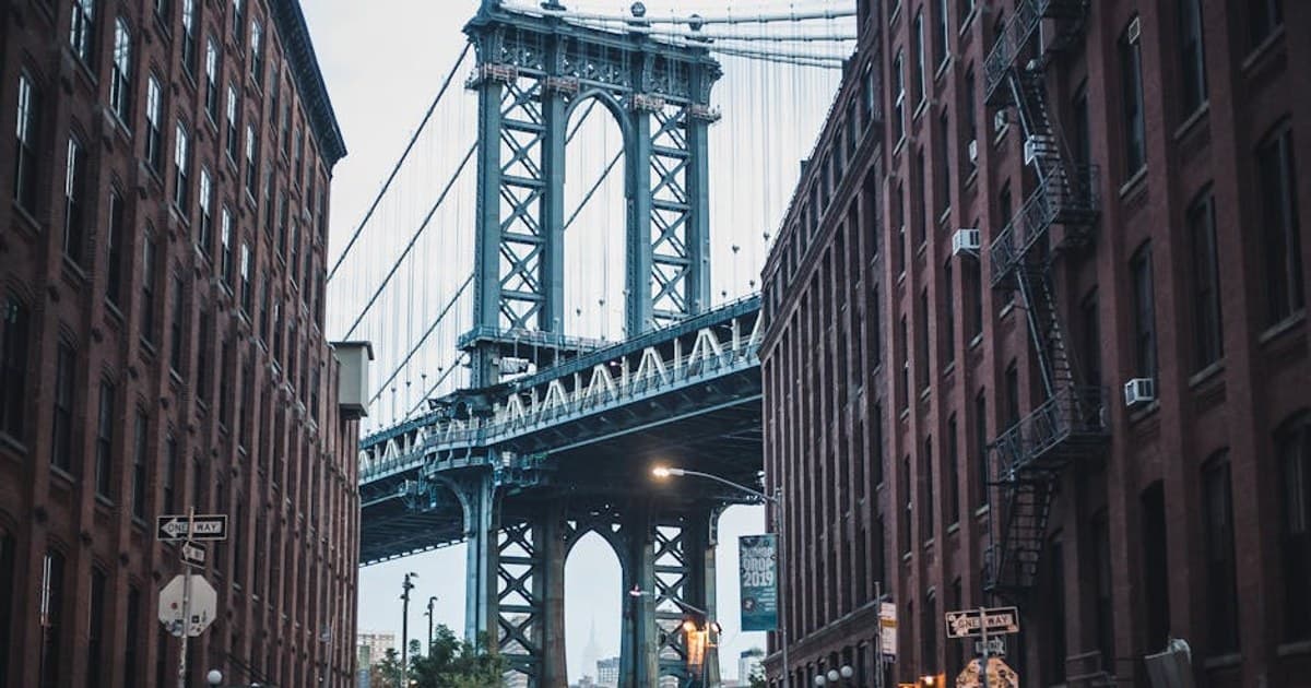 Iconic view of the Manhattan Bridge framed by urban buildings in Brooklyn, NY.