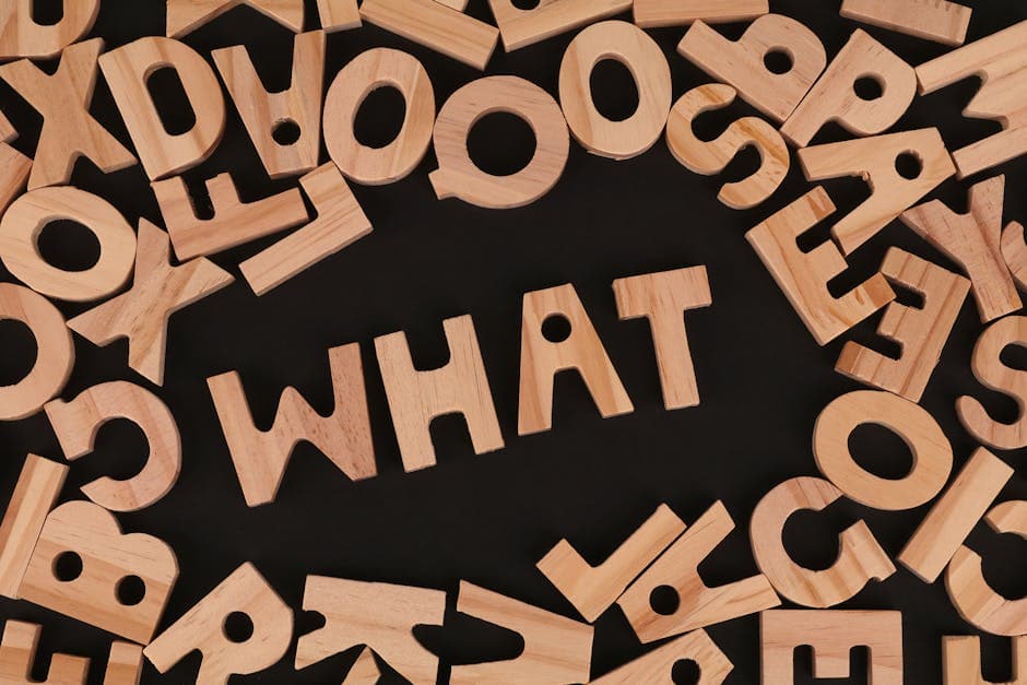 Artistic arrangement of wooden letters spelling 'WHAT' on a black background, offering creative inspiration.