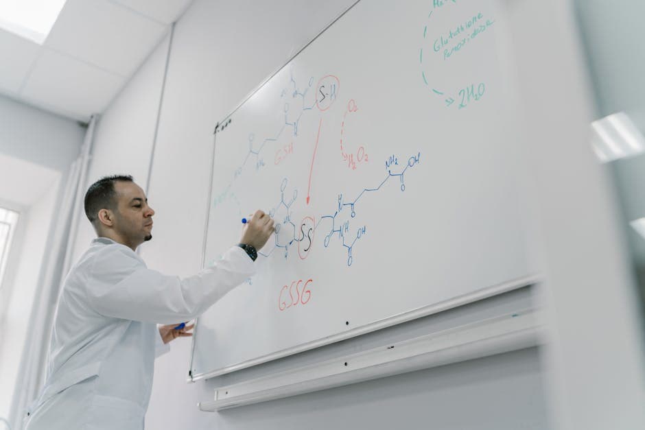 Male teacher explains chemical equation on whiteboard in science classroom setting.