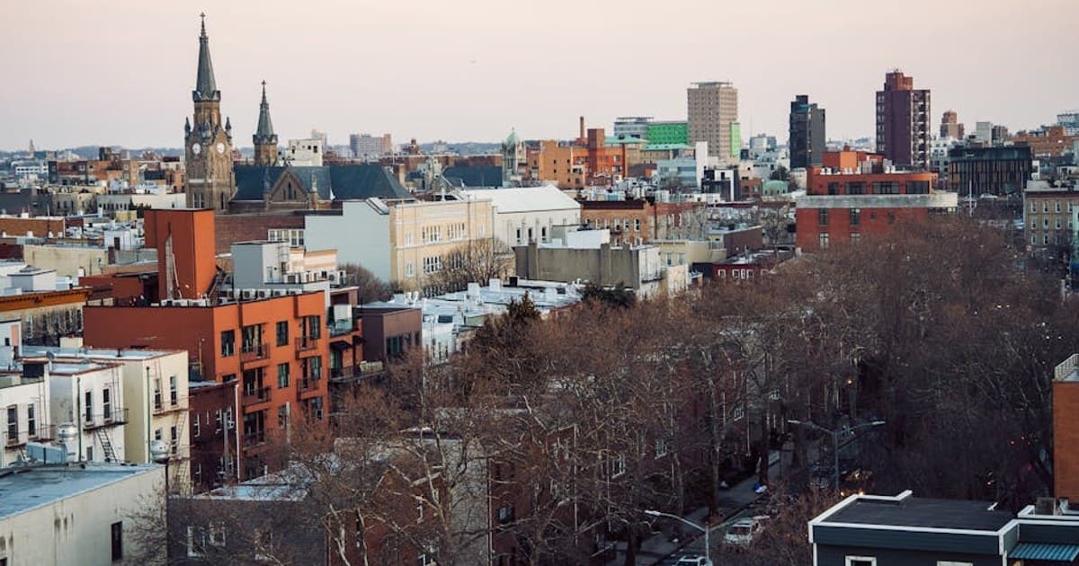 Aerial view of Brooklyn's cityscape featuring church spires and urban architecture at dusk.