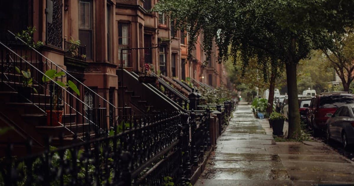 Quaint urban street view of brownstone homes on a rainy New York day.